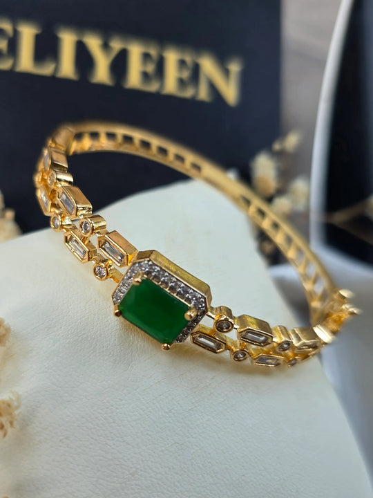 Close-up of rectangular emerald stone with cubic zirconia halo and gold bangle — Eliyeen