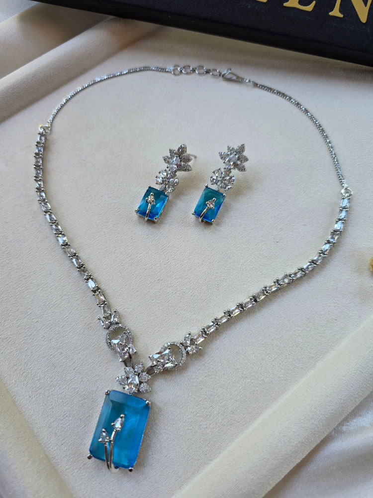 Deep aquamarine rectangular necklace and earrings set with CZ halo — white gold plated bridal jewellery — Eliyeen
Close-up of deep aquamarine rectangular pendant with cubic zirconia border — Eliyeen
Model wearing deep aquamarine statement necklace for wedding — Eliyeen